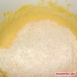 Jetzt zu der Ei-Butter-Zucker-Masse die Mandeln, das Mehl, etwas Backpulver und den Vanillezucker hinzufügen.