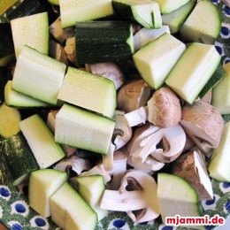 Die Zucchini vierteln und in ca. 3 cm lange Stückchen schneiden. Champignons vierteln. Auf eine große Schale legen, die noch in den Wok passt.