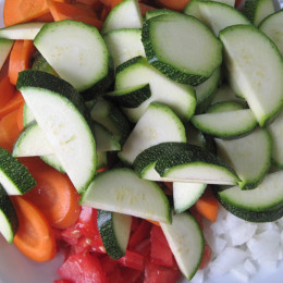 In der Zeit 2 Zwiebeln, 4 Knoblauchzehen, 1 Zucchini, 2 Möhren, 2 Tomaten kleinschneiden.