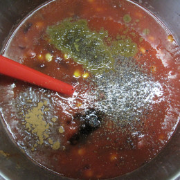 Die 2 Gläser Tomaten unterrühren. Mit Balsamicoessig, Salz, Pfeffer, Zimt, Kreuzkümmel und nach Wunsch noch etwas Chayenne-Pfeffer abschmecken. 1 h auf kleiner Flamme kochen lassen.